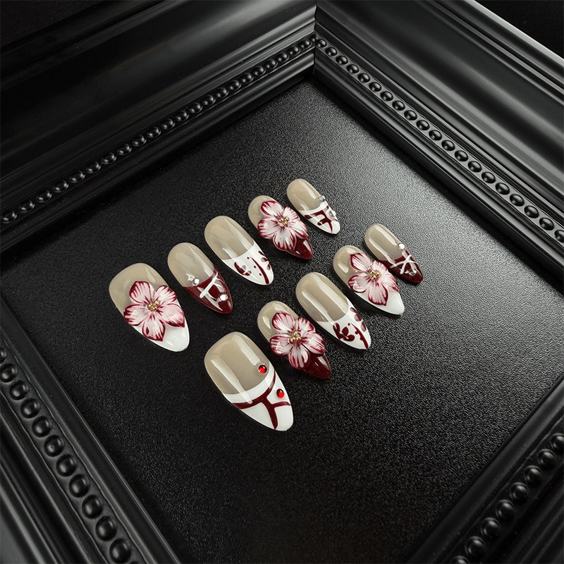Burgundy and white French tip almond nails with red rhinestone accents